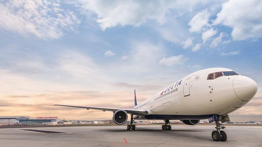 A frontal view of Delta's Boeing 767-400 model sits on the runway while a wisped sky overlooks. 