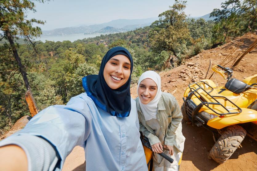 Two people pose for a selfie in front of an ATV in one of the images available as part of Delta's joint "Faces of Travel" campaign and database.