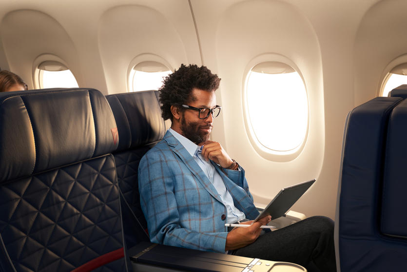 A man works on a tablet while seated in Delta domestic first class.