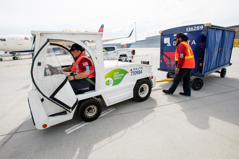 Delta Ramp Agent Sinai Pauni (left) and Aircraft Load Agent Thomas Tuikolovatu (right) operate an electric bag tractor at Salt Lake City International Airport (SLC).
