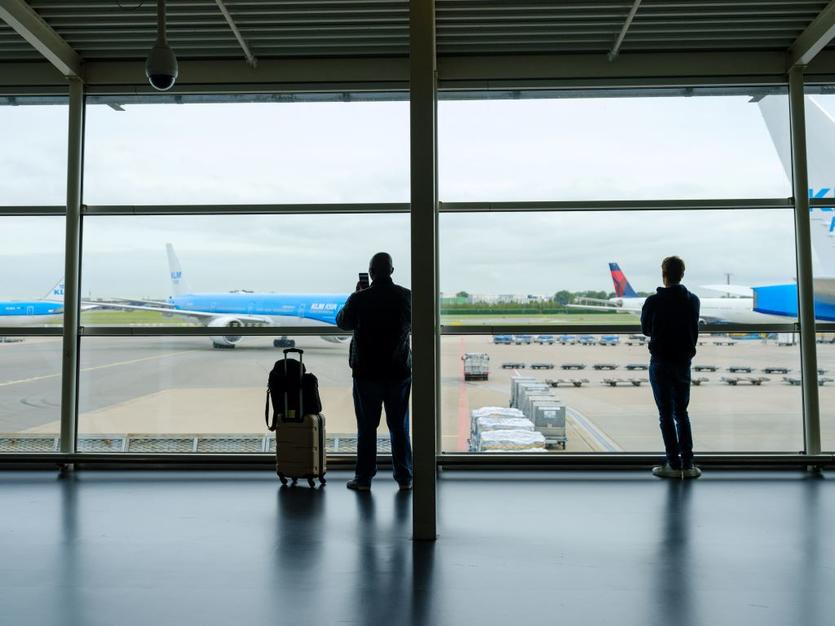 Customers at Schiphol Airport in Amsterdam with Delta and KLM aircraft in the background.