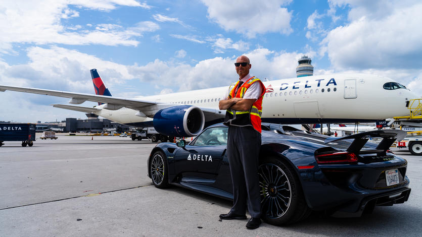 Delta Elite Services Ambassador Dan Lavker waits for a customer next to a Porsche 918 Spyder and an Airbus A350 jet at Hartsfield-Jackson Atlanta International Airport.