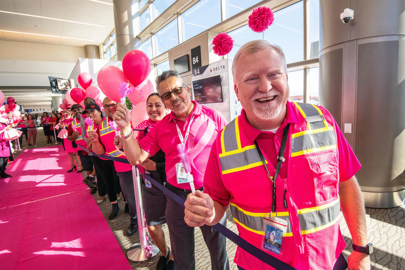 Delta people, dressed in all pink, cheer on the breast cancer survivors who flew on Delta's Breast Cancer One charter flight.