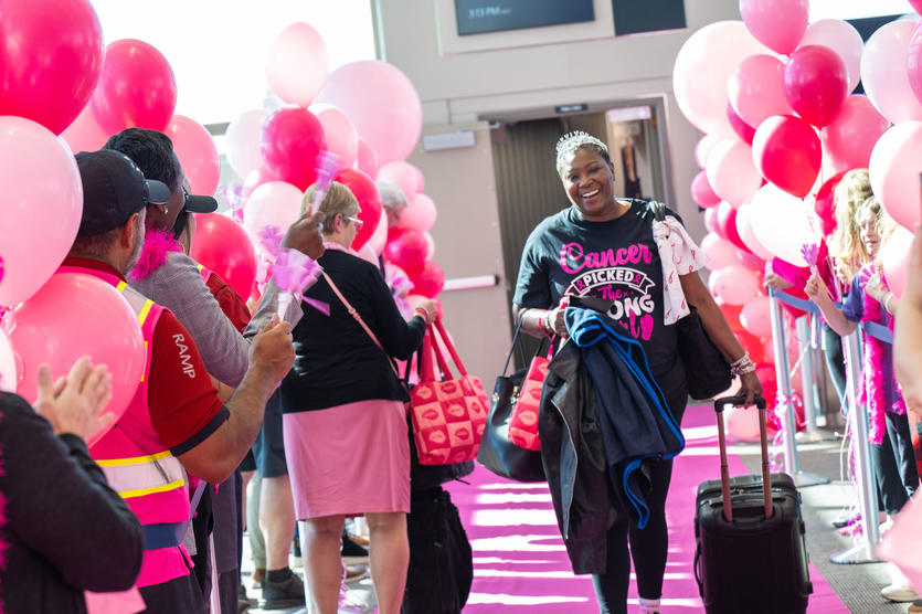 A breast cancer survivor walks down a pink runway after disembarking the Breast Cancer One charter flight.