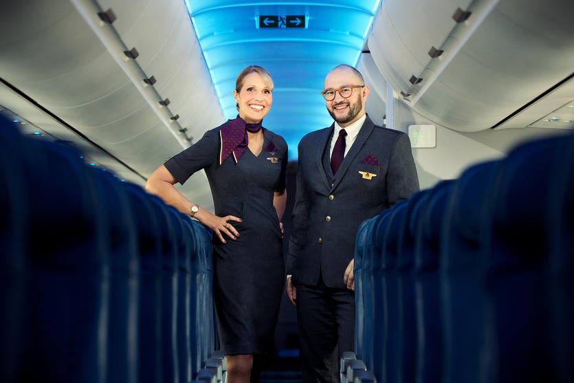 Two Delta flight attendants standing on an aircraft