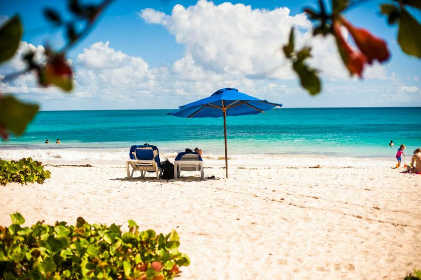 A couple sitting on lawn chairs on an umbrella in Barbados.