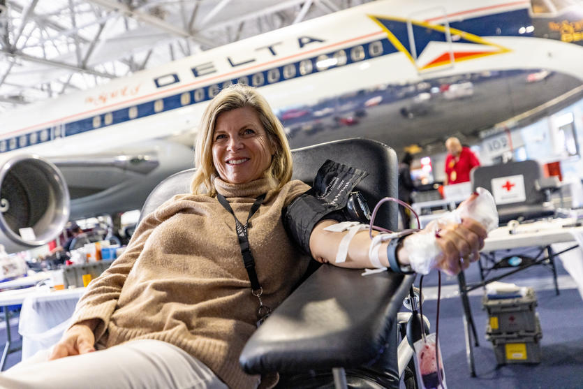 A woman sits in front of a Delta jet in the Delta Flight Museum, giving blood during one of Delta's many blood drives.