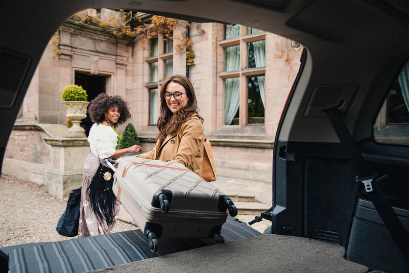 Two people unload suitcases from their vehicle in this stock photo taken in April 2019.