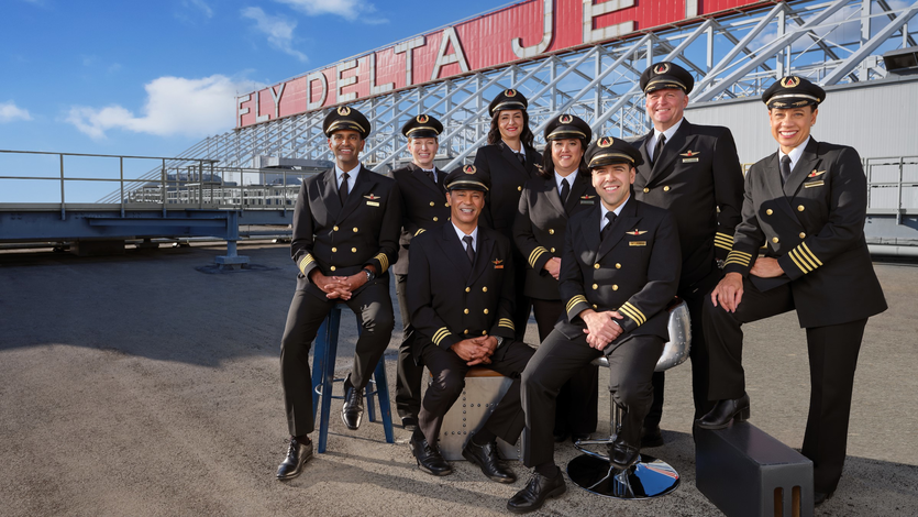 Delta pilots pose in front of a "Fly Delta Jets" sign.