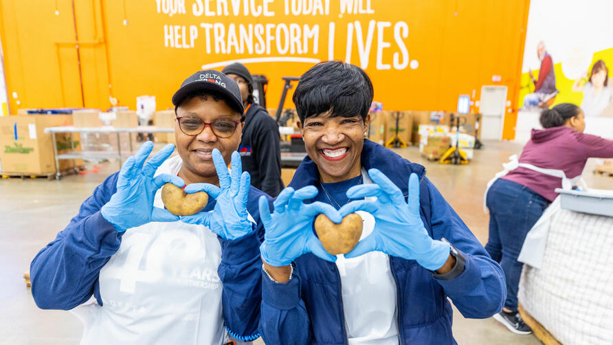 Delta employee volunteers holding heart-shaped potatoes