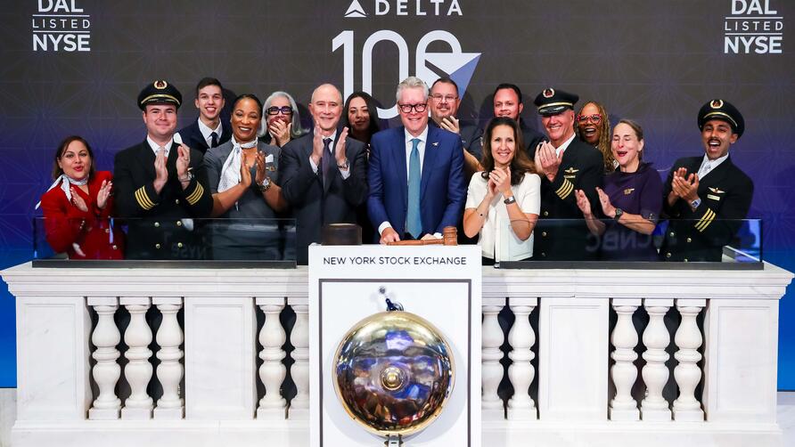 Ed standing in front of the NYSE bell with a group of employees, all clapping