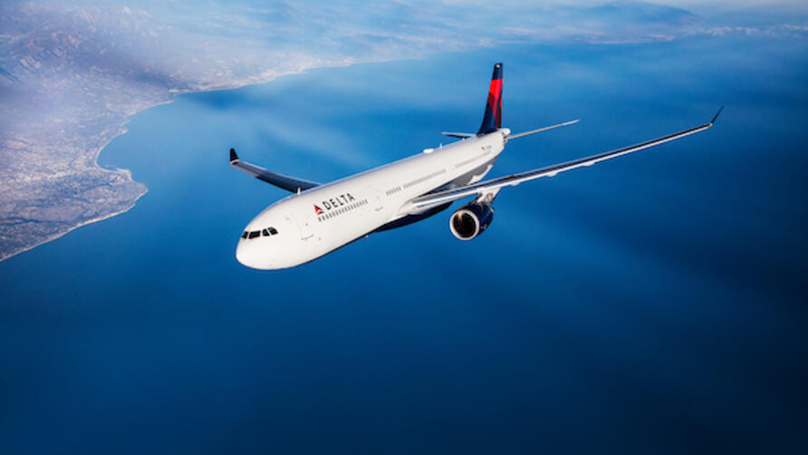 A Delta branded A330 flies in the sky. 