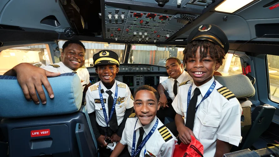 DREAM Flight participants pose with flight crew members in an aircraft cockpit during a behind-the-scenes aviation experience.