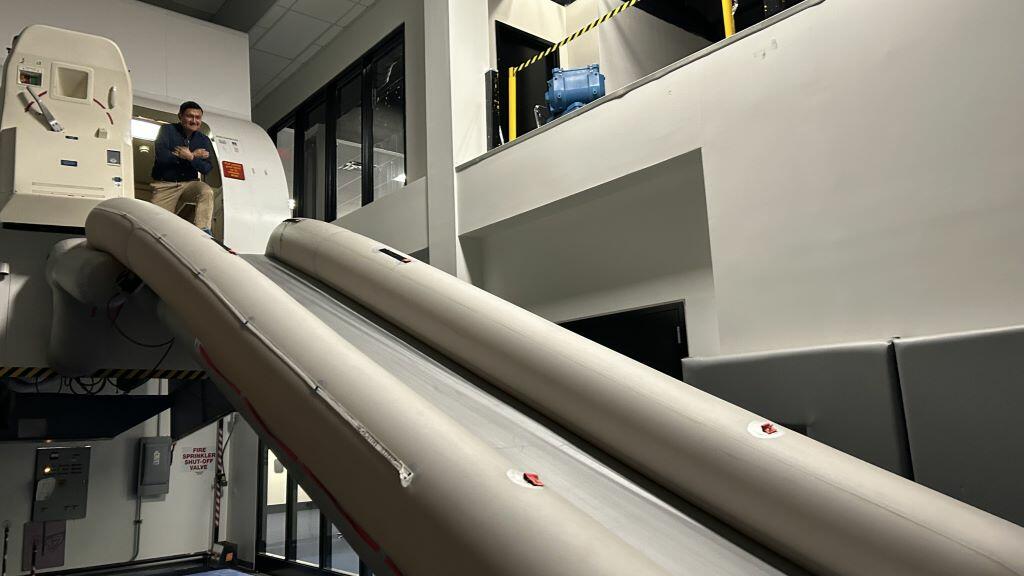 Todd O., Delta's most frequent flyer, prepares to take the plunge down the slide after an emergency flight simulator test. 