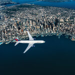 A 767-300 flies over Seattle skyline.