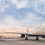 A frontal view of Delta's Boeing 767-400 model sits on the runway while a wisped sky overlooks. 