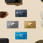 Flat lay of Delta SkyMiles American Express Cards surrounded by travel essentials, including a passport, camera, sunglasses, headphones, and luggage accessories.