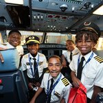 DREAM Flight participants pose with flight crew members in an aircraft cockpit during a behind-the-scenes aviation experience.