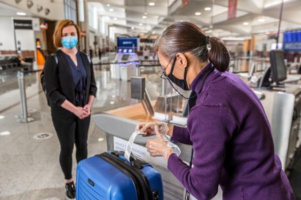 A gate agent helps a passenger check a bag.