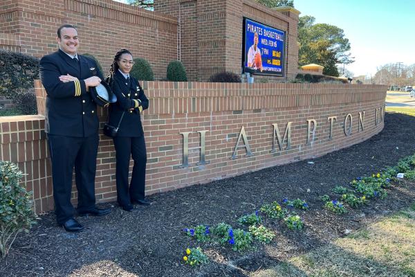 Two aviators stand outside of Hampton University.