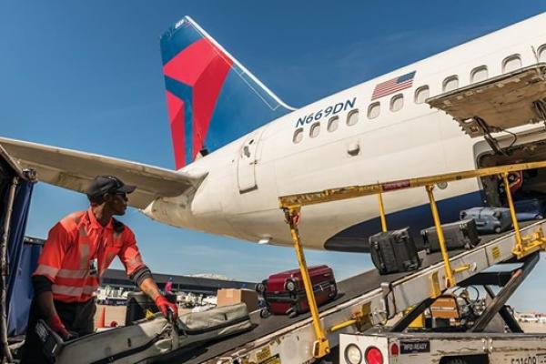 A Delta employee loads baggage onto a plane.