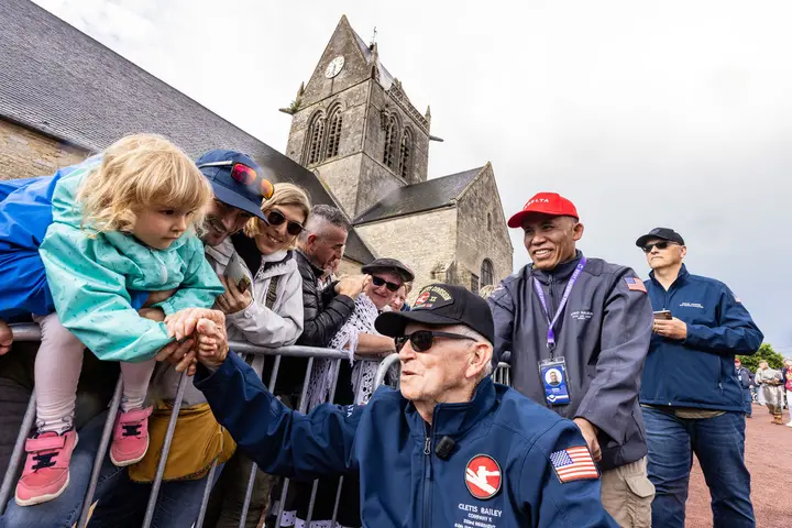 Delta’s Noni Balboa escorts Cletis Bailey through a parade in St. Mere Eglise.