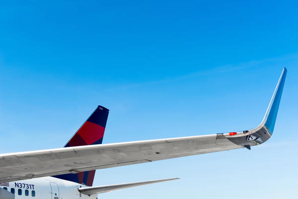 A view of a 737-800 wing and tail with a background of a clear sky.
