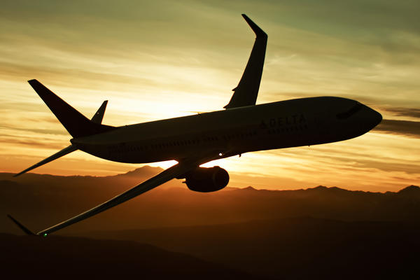 A 737-900 flies with a sunset in the background, creating a silhouette of the aircraft.