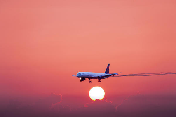 A 757-300 in flight with a red-hued sunset and cloud background.
