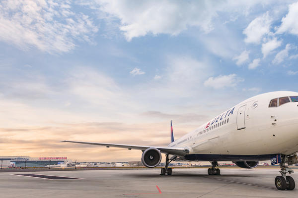 A frontal view of Delta's Boeing 767-400 model sits on the runway while a wisped sky overlooks. 