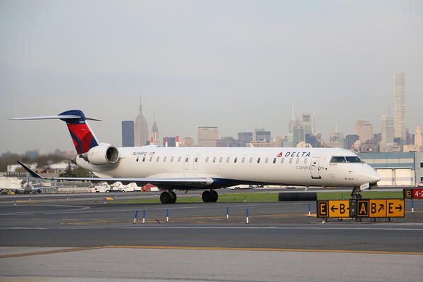 Delta's CRJ-900, one of the three aircraft in the Bombardier collection, prepares for takeoff while overlooking a bustling city skyline.