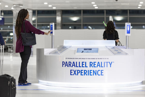 Female customer using Parallel Reality screen to check-in at a Parallel Reality Experience kiosk