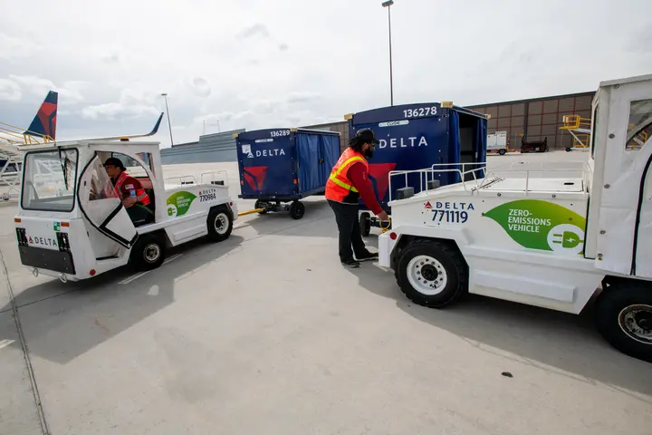 Delta Ramp Agent Sinai Pauni (left) and Aircraft Load Agent Thomas Tuikolovatu (right) operate electric bag tractors at Salt Lake City International Airport (SLC).