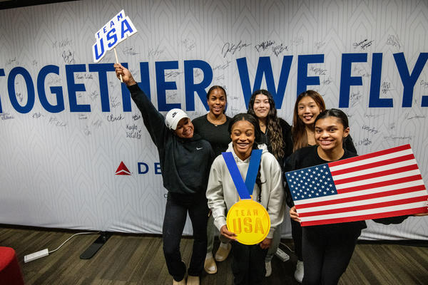 Team USA athletes pose in front of a wall in Delta's customized athlete lounge in the ATL International Terminal.