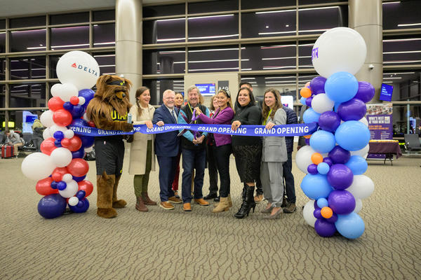 A group cuts a ribbon to mark Delta's complete of the Concourse A expansion at Salt Lake City International Airport.