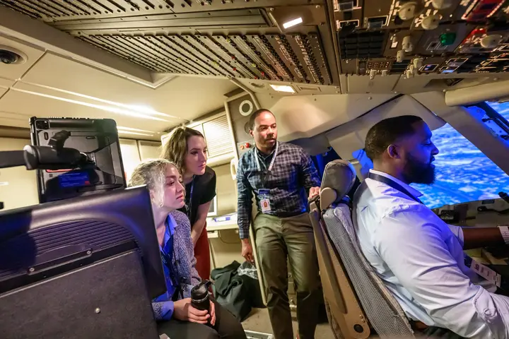 First Officer Jerome Wellons (middle) runs a flight simulator for Propel Company Path Program participants Justin Thomason, Hannah Martin and Alex Zawadzki.