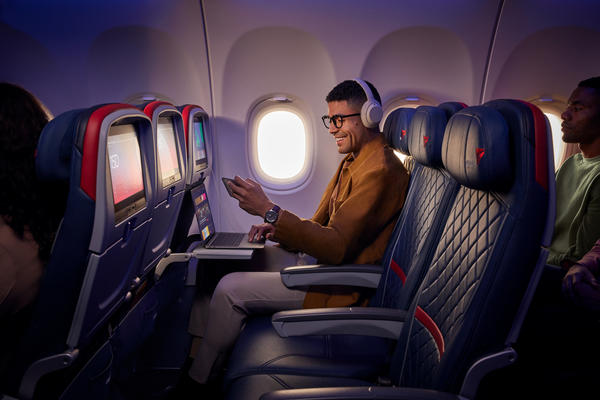 A customer uses Delta's fast, free Wi-Fi on board on their smart phone and laptop.