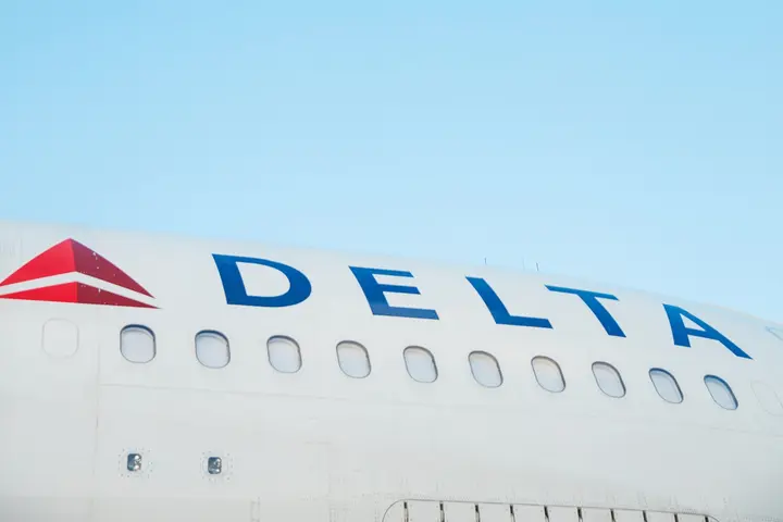 The side of a Delta aircraft against a blue sky