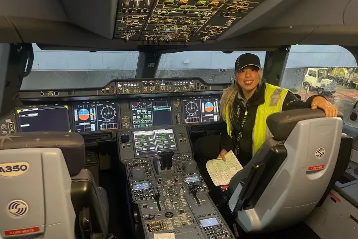 Delta TechOps employee Jessie Hekimian sits in the flight deck of an airplane.