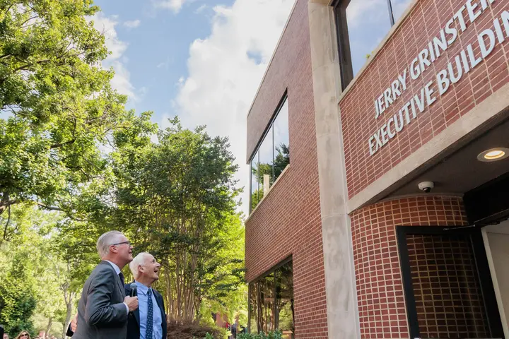 Delta CEO Ed Bastian and former Delta CEO Jerry Grinstein look up at a building.