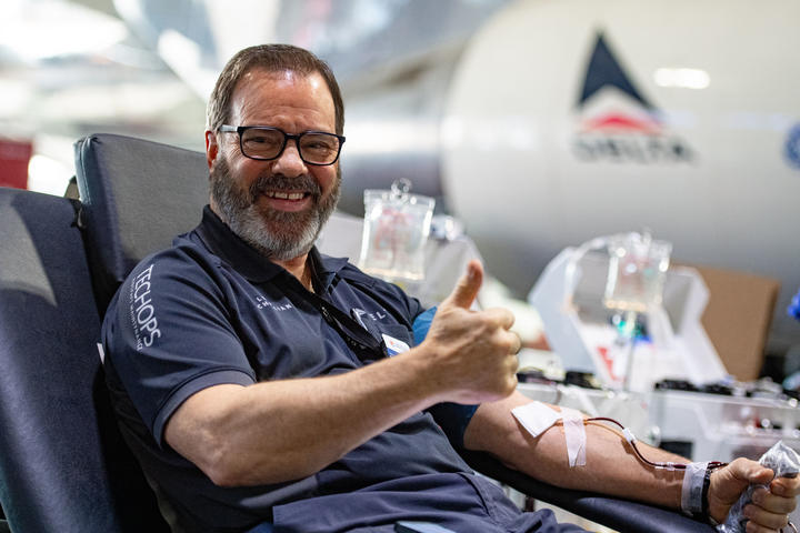 A Delta TechOps employee gives a thumbs up while donating blood.