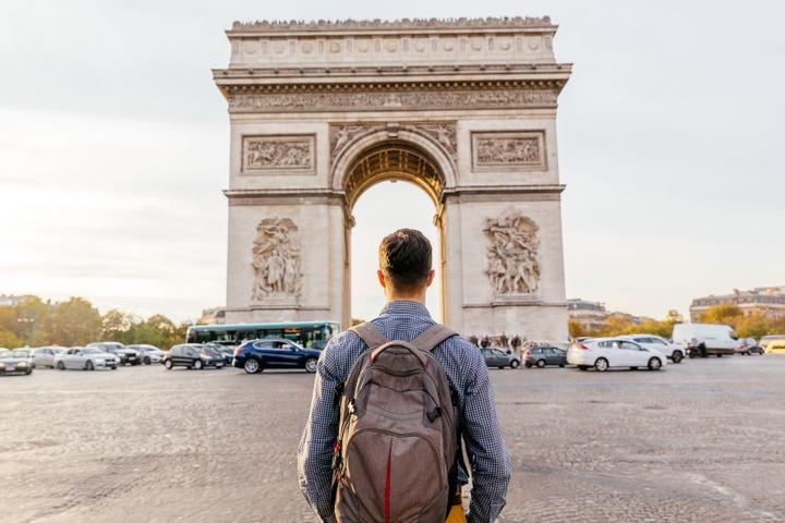 A traveler stands in front of the Arc de Triomphe in Paris, France.