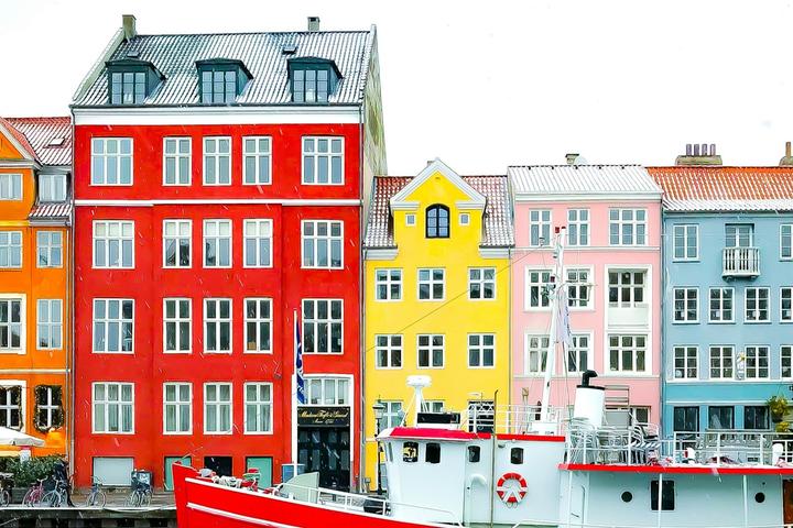 Nyhavn district with boats on water canal and colorful row of old houses in Copenhagen, Denmark