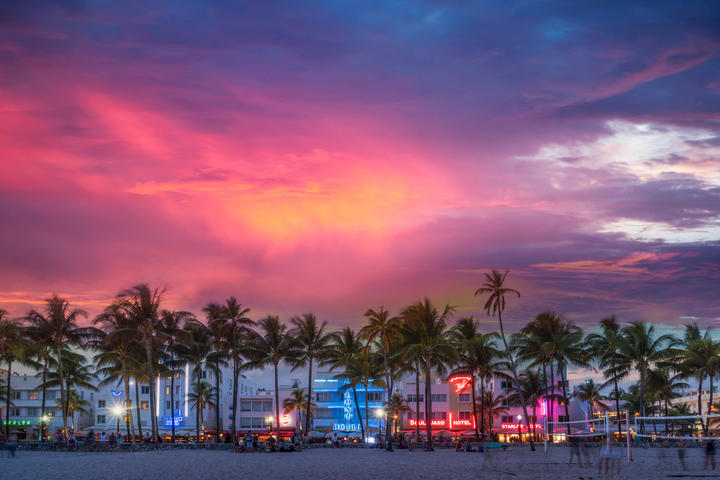 A sunset view of South Beach, Miami, complemented with neon signage and palm trees.