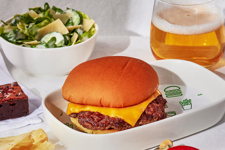 A Shake Shack burger with a side of chips, a salad, and burger fixings.