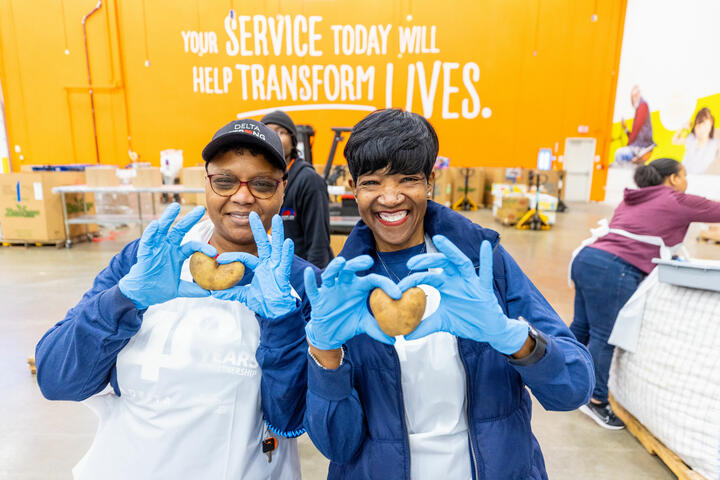 Delta employee volunteers holding heart-shaped potatoes