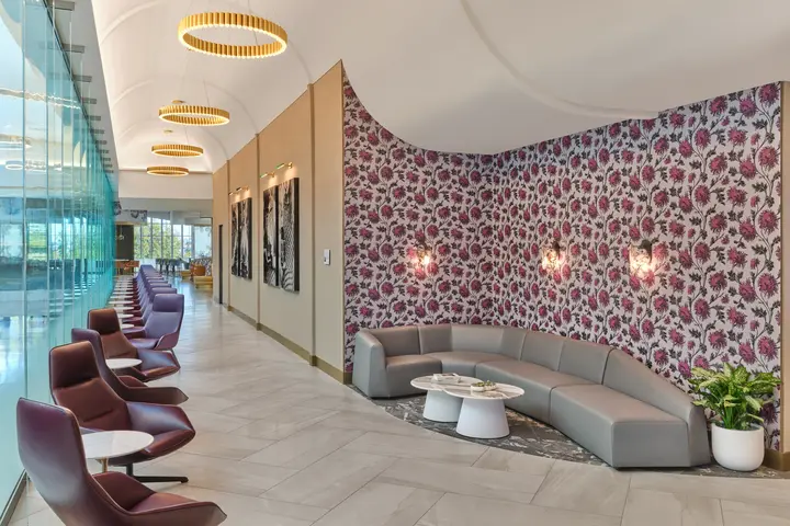 Interior of Delta's new CLT Sky Club, showing pink floral wallpapered wall and long windowed corridor.
