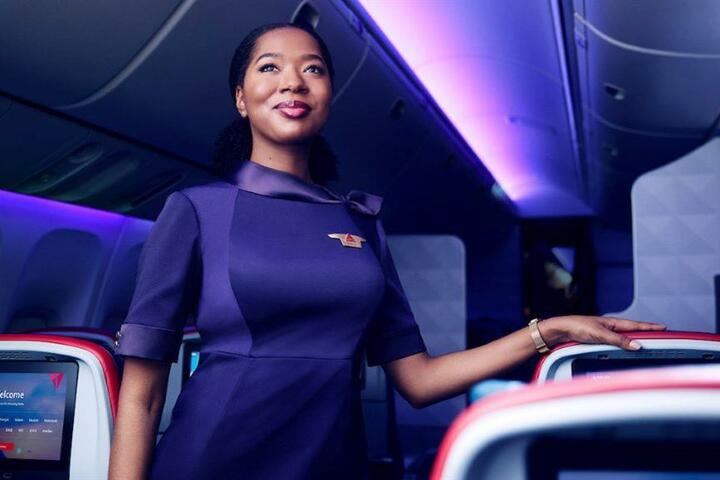 A Delta flight attendant stands in the row of a cabin