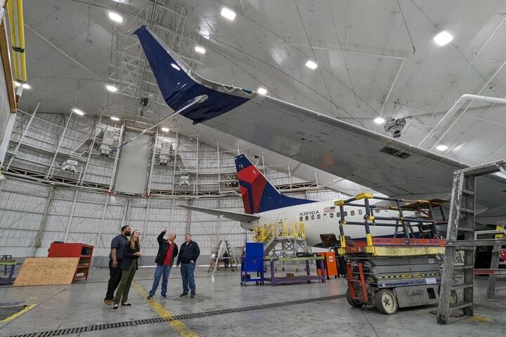Group of people looking up at airplane winglet.