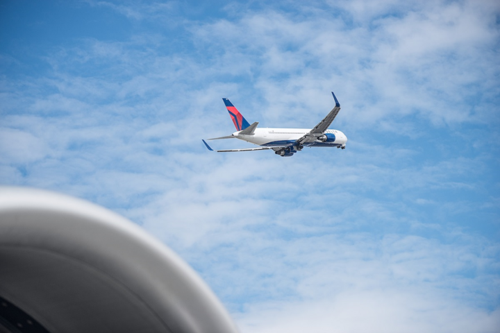 Delta 767 aircraft shortly after takeoff with blue sky and clouds in background